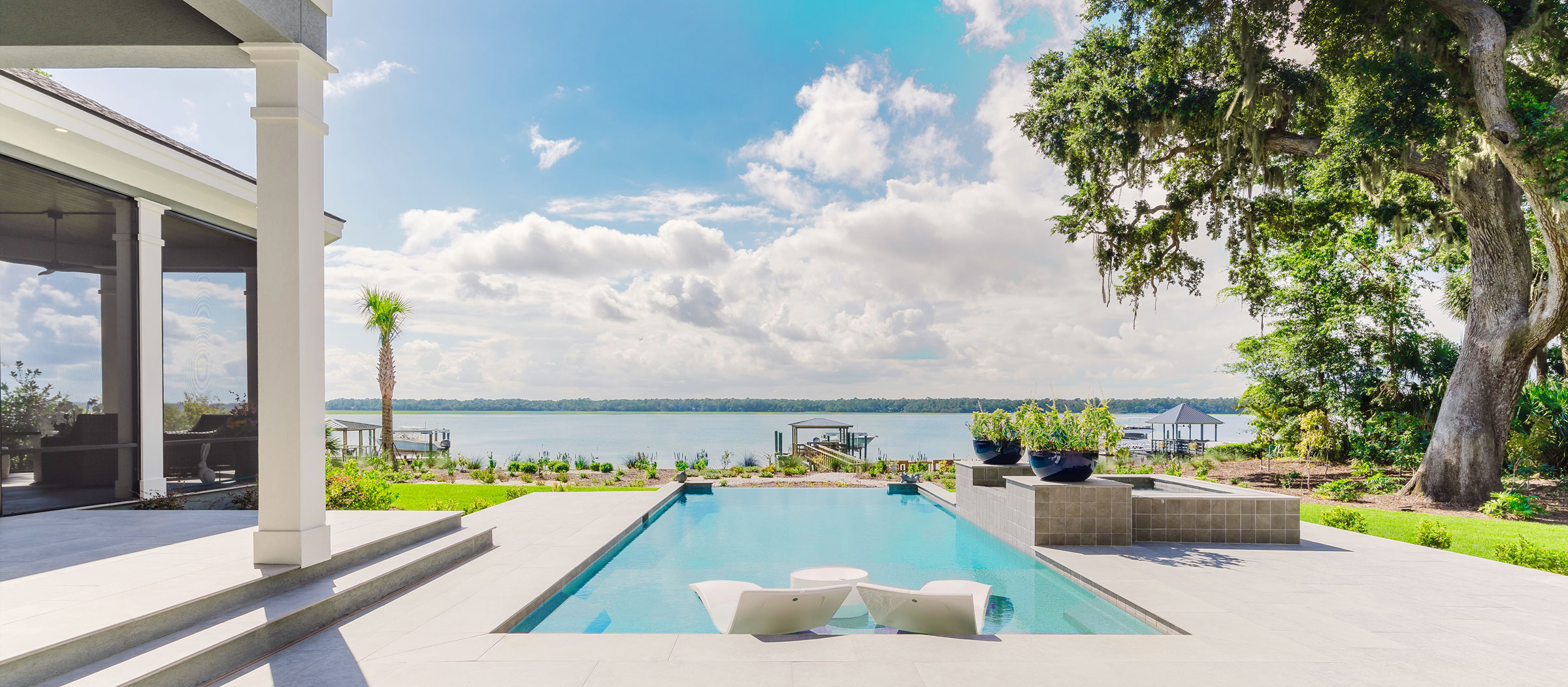 A photograph showing a new home's gorgeous waterside swimming pool stretching out from the veranda toward the coastal waterway.