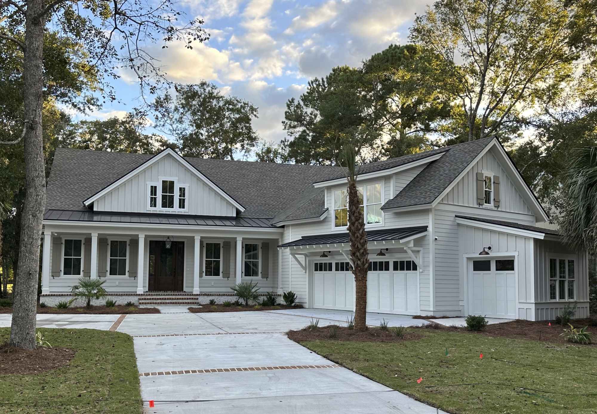 A large, modern farmhouse-style house with a gray roof, white siding, and a spacious two-car garage.