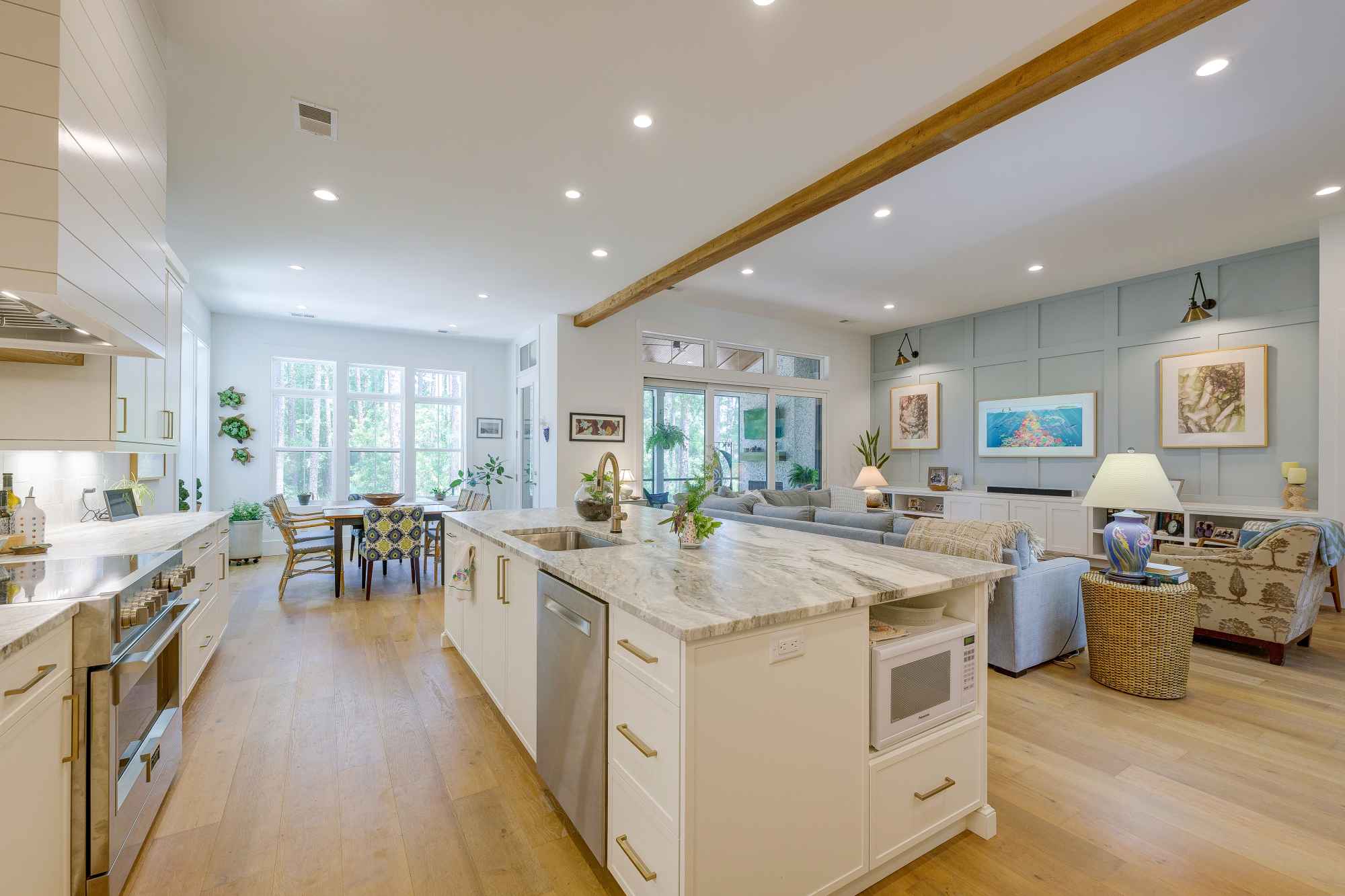 Spacious open-concept kitchen and living room with modern decor, featuring a large island, white cabinets, cozy seating, and bright natural light.