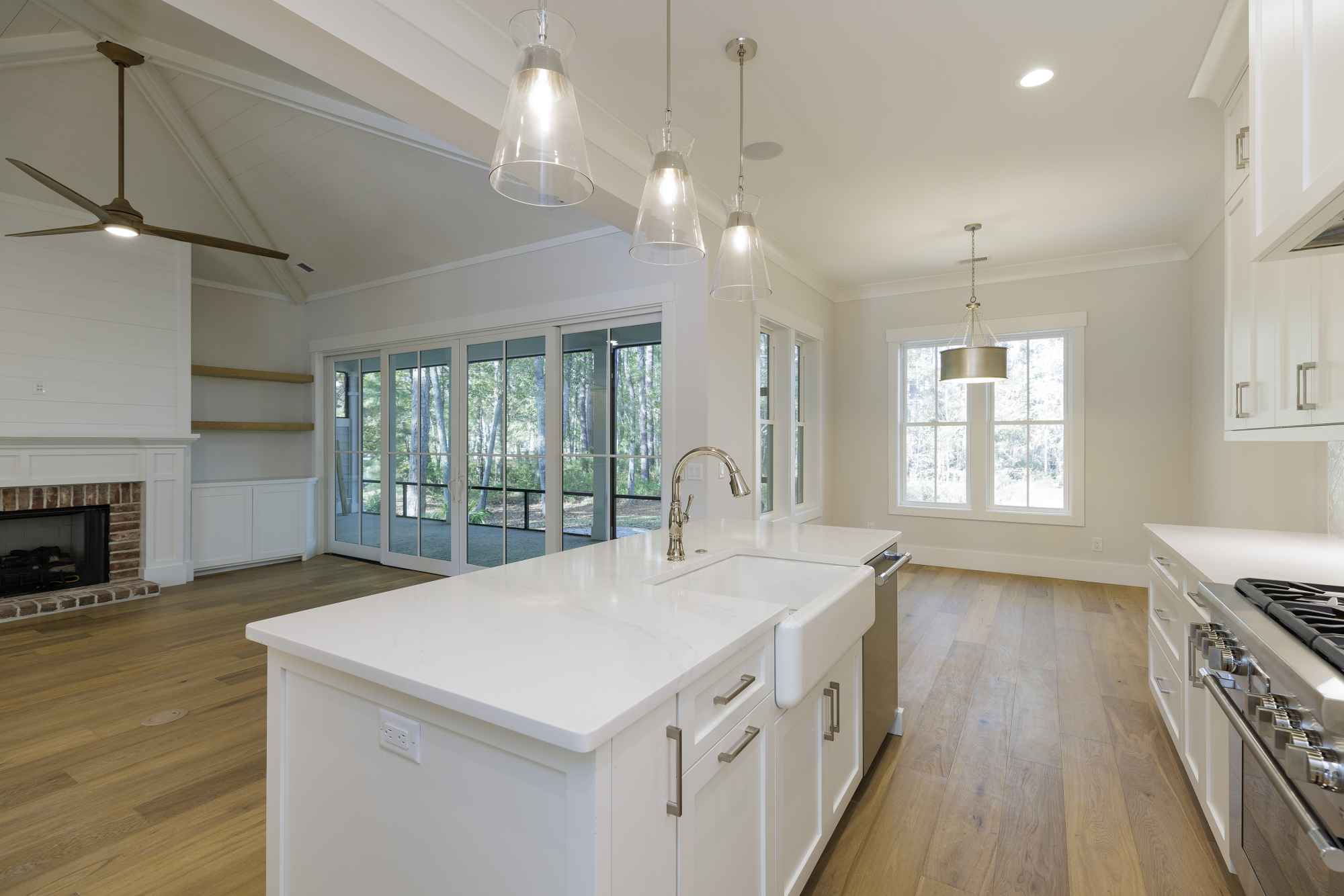 Bright, modern kitchen with white cabinets and a central island featuring a farmhouse sink. Open layout with hardwood floors and large windows.